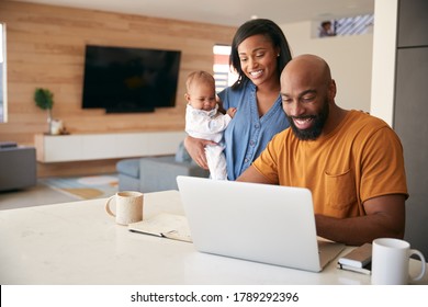 African American Family With Baby Daughter Using Laptop To Check Finances At Home