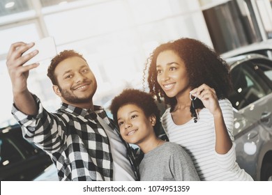 African American Family At Car Dealership. Mother, Father And Son Are Taking Selfie In Front Of New Grey Car.