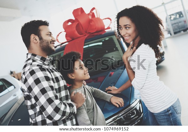 African american family at car\
dealership. Father, mother and son near new blue car,\
happy.