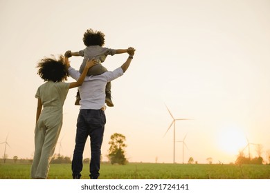African american family in the community with wind generators turbines, Wind turbines are alternative electricity sources, the concept of sustainable resources and Renewable energy. sunset. 