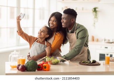 African American Family Cooking And Making Selfie On Smartphone Posing While Cutting Vegetables For Salad In Modern Kitchen At Home. Parents And Daughter Having Fun While Preparing Dinner - Powered by Shutterstock