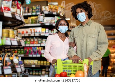 African American Family Couple Doing Grocery Shopping Walking With Full Shop Cart Wearing Surgical Face Masks In Groceries Store. Supermarket Buyers, Consumerism Concept