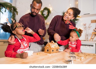 African American family decorating a gingerbread house together on Christmas day. Christmas moments with kids at home concept - Powered by Shutterstock