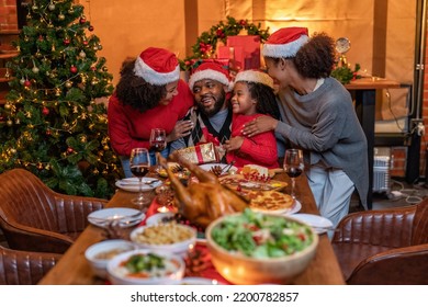 African american family decoration gift box in background on festive christmas tree and cheerful serving roasted turkey and happy when young daughter giving gift box to father all hug each other
 - Powered by Shutterstock