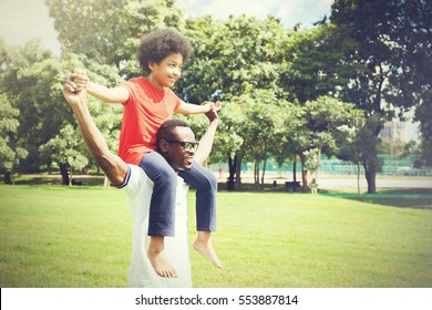 African American family doing piggyback and having fun in the outdoor park during summer