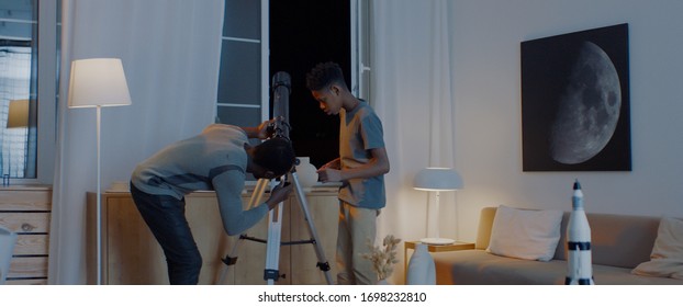 African American family - father and son, using telescope to explore moon surface. Stay home, learning from home, quarantie - Powered by Shutterstock