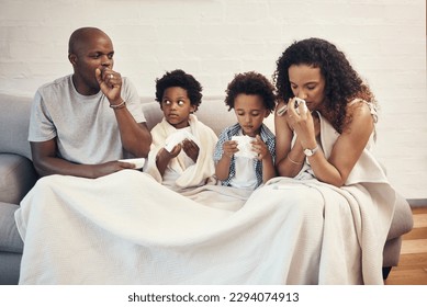 African american family of four feeling sick and unwell with flu and cold while covered in a blanket on a couch. Parents and two kids coughing and blowing nose from seasonal allergy symptoms and covid - Powered by Shutterstock