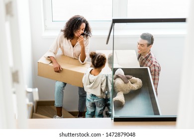 African American Family Going Upstairs With Boxes While Kid Looking At Father