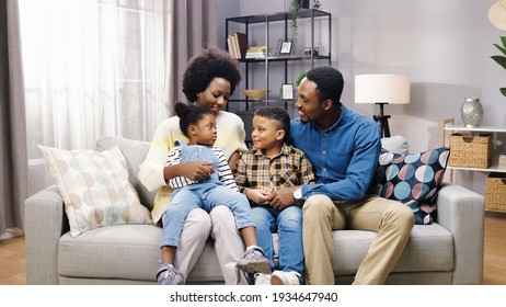 African American Family With Kids Sitting On Sofa In Room, Looking At Camera And Smiling, Positive Emotions, Parents With Children Gathered Together At Home Parenting Concept