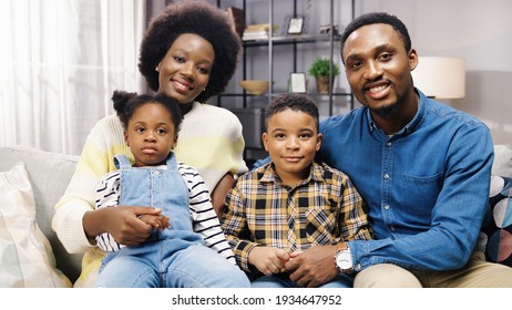 African American Family With Kids Sitting On Sofa In Room, Looking At Camera And Smiling, Positive Emotions, Parents With Children Gathered Together At Home Parenting Concept