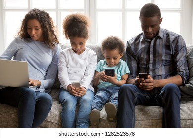 African American Family With Kids Using Laptop And Mobile Phones At Home, Black Parents And Little Children Addicted To Devices, Gadgets Dependence Overuse, Internet Social Media Addiction Concept