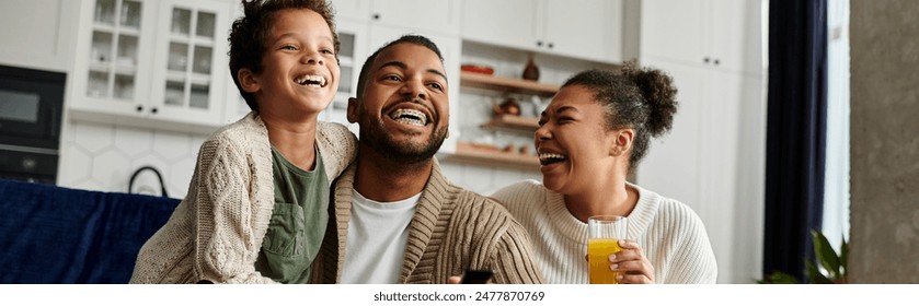 African american family laughing, holding glasses of orange juice. - Powered by Shutterstock