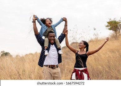 African American Family Looking very Happy outdoors. Happy black family are having Fun in the Nature. Smiling Young family Laughing in Forest.
