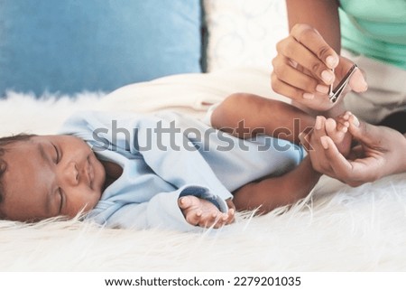 African American family, A mother is using a nail clipper for her 1-month-old baby newborn son who is sleeping on a white bed, to health care and baby newborn concept.