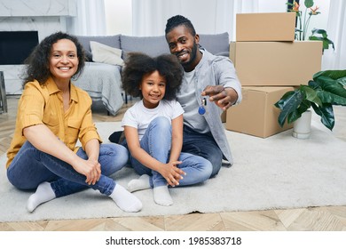 African American family moves into a new home. Father, mother, and daughter are happy sitting on a house floor after unpacking things. Buying or renting a house for a young family