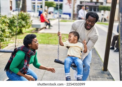 African american family playing on swing at playground - Powered by Shutterstock