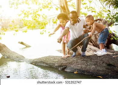 African American Family Pointing And Standing On Tree Around The Lake