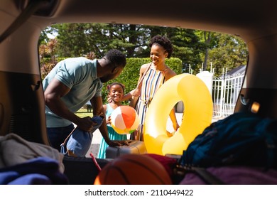 African American Family Putting All The Luggage In The Back Of The Car. Family Trip And Vacation Concept, Unaltered.