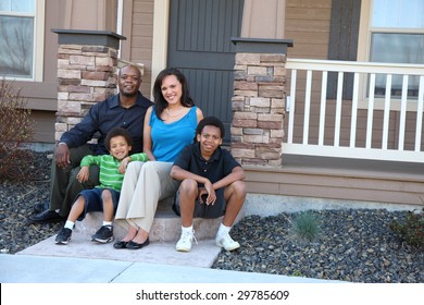 African American Family Sitting Together On Front Steps Of Home