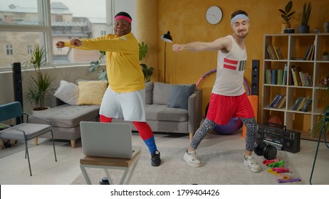 African American Fat Guy Engaged In Sports With Fitness Instructor Doing Light Stretching Warm-up Exercises Indoors. Funny Workout. Training. Fun Concept.