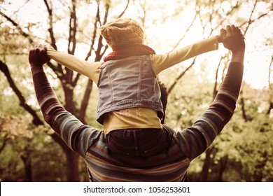 African American Father Carrying His Daughter On Shoulders. From Back.