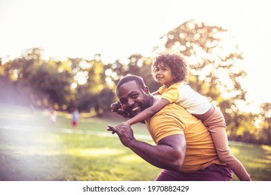 African American Father And Daughter Having Fun Outdoors. Father Carrying Daughter On Piggyback.