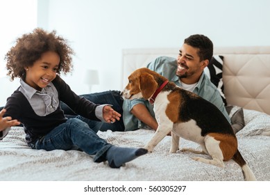 African american father and daughter spending time together with a dog on a bed. - Powered by Shutterstock