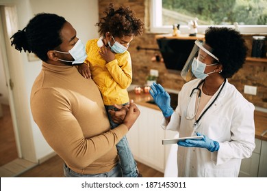 African American father and daughter talking to their family doctor who is visiting them at home during coronavirus pandemic. Focus is on doctor.