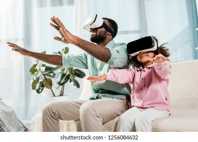 african american father and daughter using virtual reality glasses and smiling in living room - Powered by Shutterstock