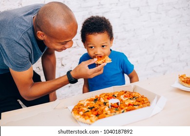 African American Father Feeding His Cute Son With Pizza. Warm Family Concept. Warm Family, Father And Son Relationship