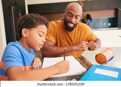 African American Father Helping Son Studying Homework In Kitchen - Powered by Shutterstock