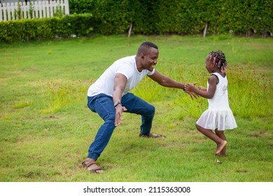 African American Father Is Holding His Little Daughter Hand And Having A Good Time Together While Playing Outside The House Around The Neighborhood Park During Summer Time