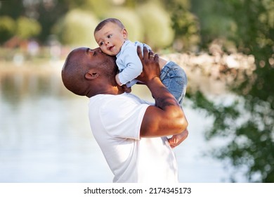 African American Father Kisses, Holds On Arms And Loves Child Son Mixed Race Outdoors In Summer