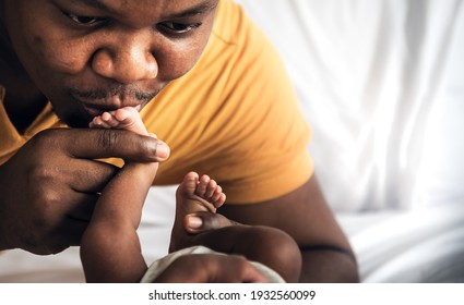 An African American Father Kissing Foot, His 12-day-old Baby Newborn, With Love And Happy, Concept To African American Family And Baby Black Skin Newborn