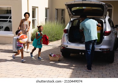 African american father putting all the luggage in the back of the car. family trip and vacation concept, unaltered.