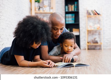 African American father reading a fairy tale fable story for kids at home. Happy family lying on the floor indoors