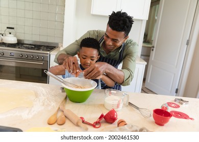 African american father and son baking in kitchen breaking eggs into mixing bowl. family enjoying quality free time together. - Powered by Shutterstock