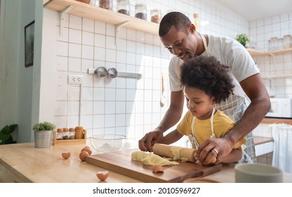 African American Father and son baking at home together. Black Child enjoying helping Dad. Brazilian family in the kitchen.