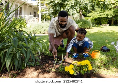 African american father and son digging dirt with tools on grassy field in backyard. Unaltered, lifestyle, gardening, family, love, togetherness, nature and childhood concept. - Powered by Shutterstock