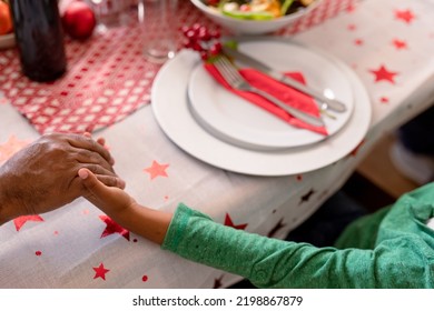 African American Father And Son Holding Hands Over Christmas Table. Christmas, Festivity And Tradition At Home.