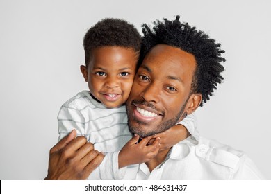 An African American father and son hug and smile for the camera on a white background.  Isolated image.  