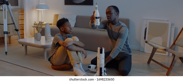 African American father and son playing together, building moon landing mission rocket together. Stay home, quarantine, science - Powered by Shutterstock