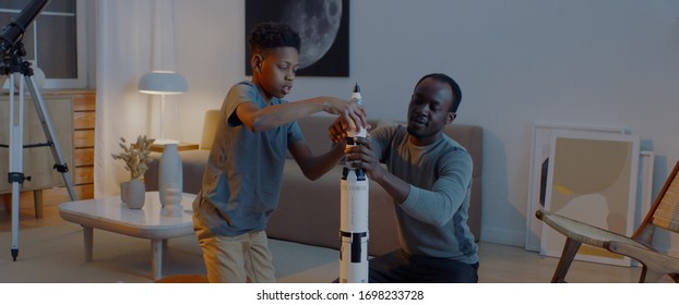 African American father and son playing together, building moon landing mission rocket together. Stay home, quarantine, science - Powered by Shutterstock