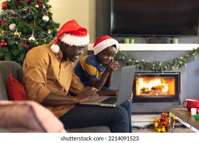 African american father and son siting on the sofa and using laptop. Christmas, family time and celebration using technology concept. - Powered by Shutterstock