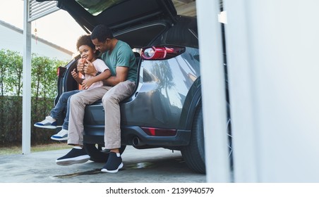 African American Father And Son Sitting In Car Trunk, Happy Family On Road Trip.