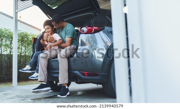 African American Father and son sitting in car\
trunk, Happy family on road\
trip.