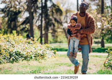 African American Father Spending Time With His Daughter In The Park. Father's Day. Father's Love. Happy Black Father Lifting His Baby Girl And Playing With Her.