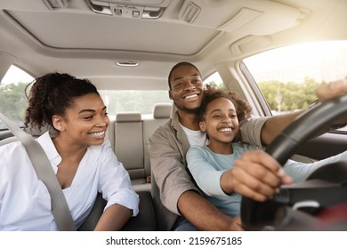 African American Father Teaching His Daughter To Drive Driving The Car Together. Happy Family Riding New Automobile In City, Having Fun Traveling By Auto. Vehicle Transportation