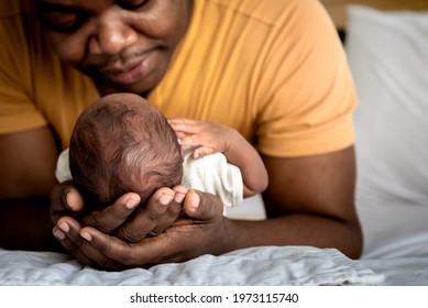 An African American Father Used Both Hands To Support His Son's Head, 12-day-old Baby Black Skin Newborn Son, Lying In Bed In A Bedroom With Happy And Protection, Concept To African Family And Newborn