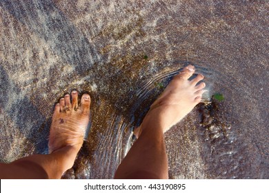 African American feet on black sand beach coast with water ripples